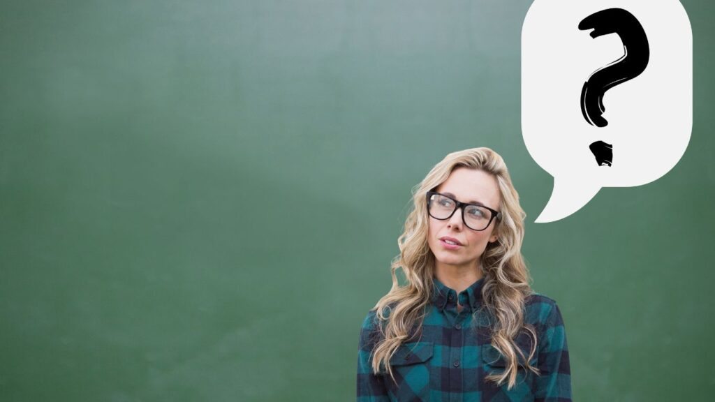 Frau mit blonden Haaren, einer Brille schaut mit leicht nach oben und stellt sich die Frage wie negative Glaubenssätze entstehen.